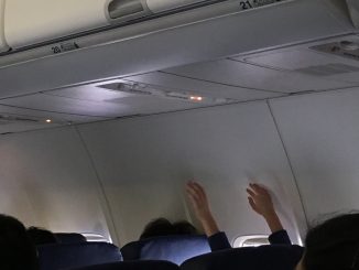 Little boy on airplane with hands up in the air during turbulence