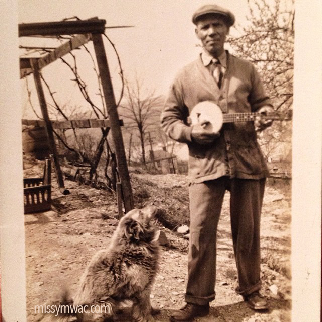 Old photo of Italian man playing a banjo with a dog sitting at his feet